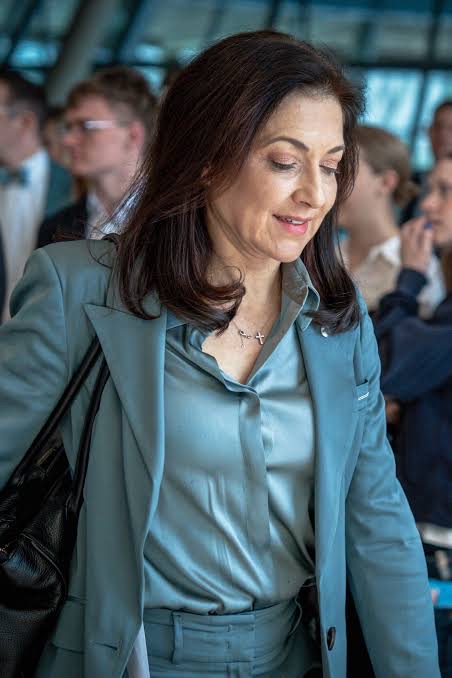 Katherina Reiche in a teal suit walking through a crowd of people