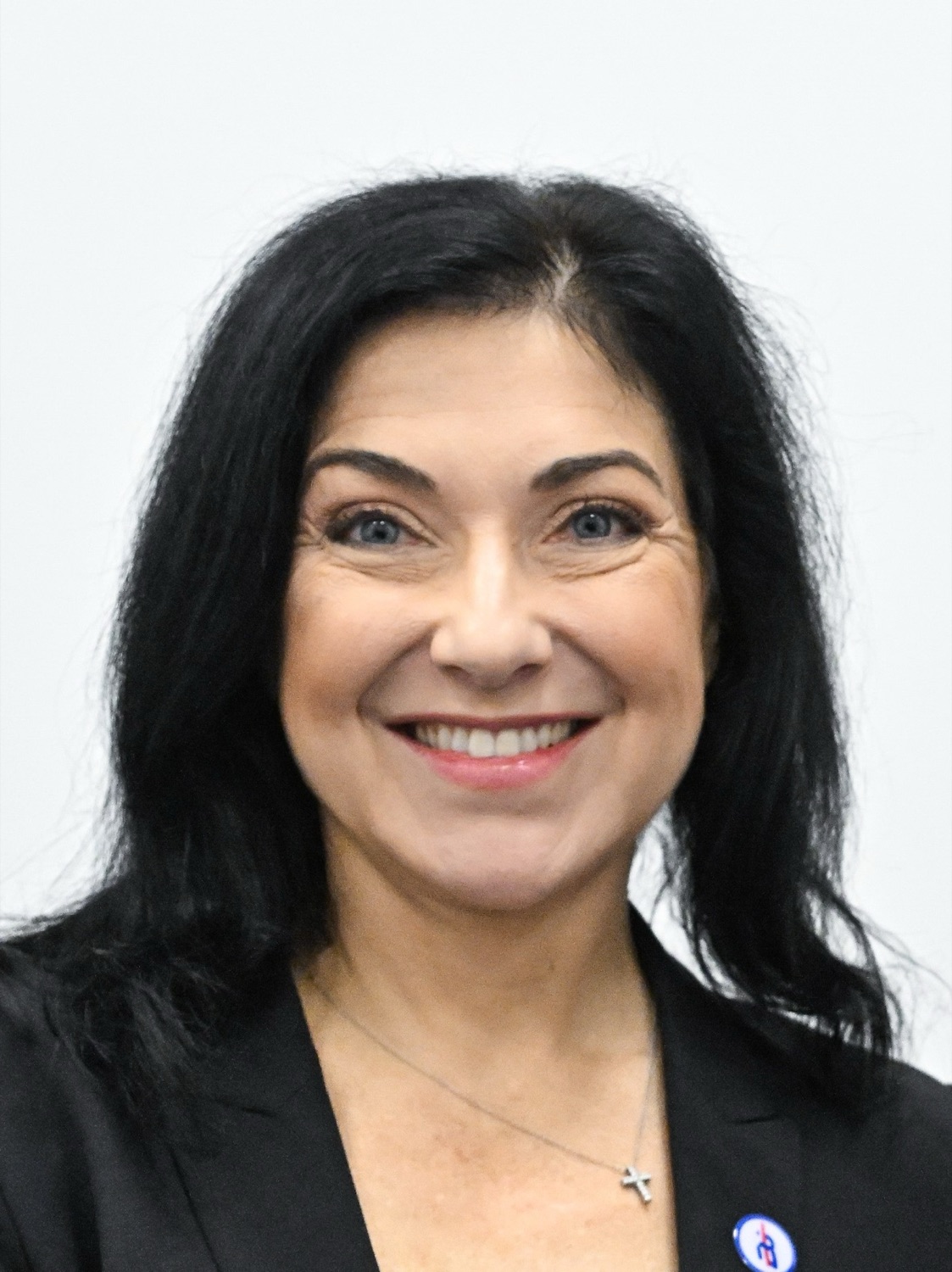 Portrait of Katherina Reiche smiling, in a dark jacket against a light background