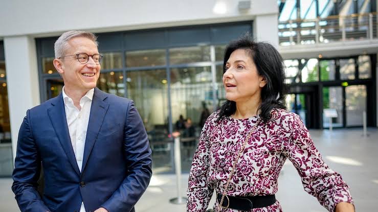 Katherina Reiche walking and talking with a colleague outside a modern glass building