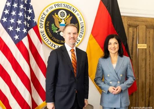 Katherina Reiche with a US official in front of the US flag and the seal of the Executive Office of the President