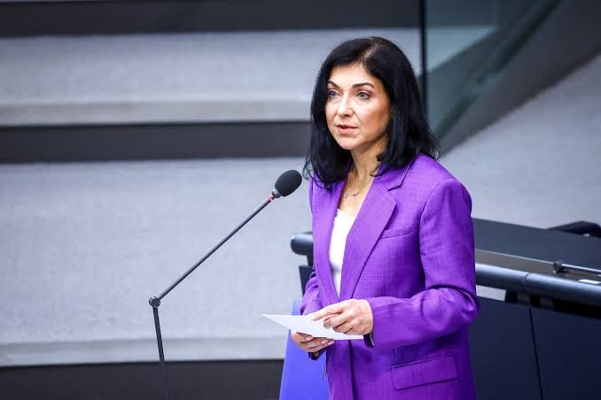 Katherina Reiche in a purple suit speaking at a lectern