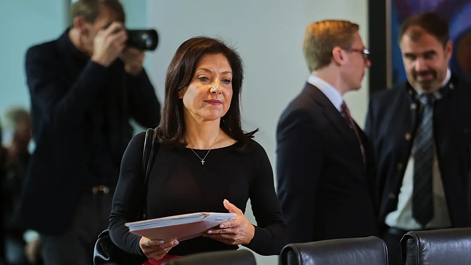 Katherina Reiche holding papers among photographers and officials