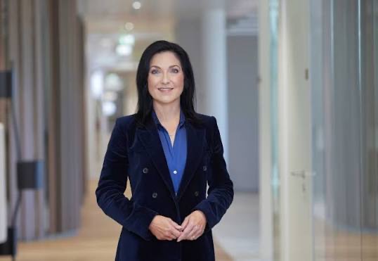 Katherina Reiche in a navy suit standing in a bright office corridor